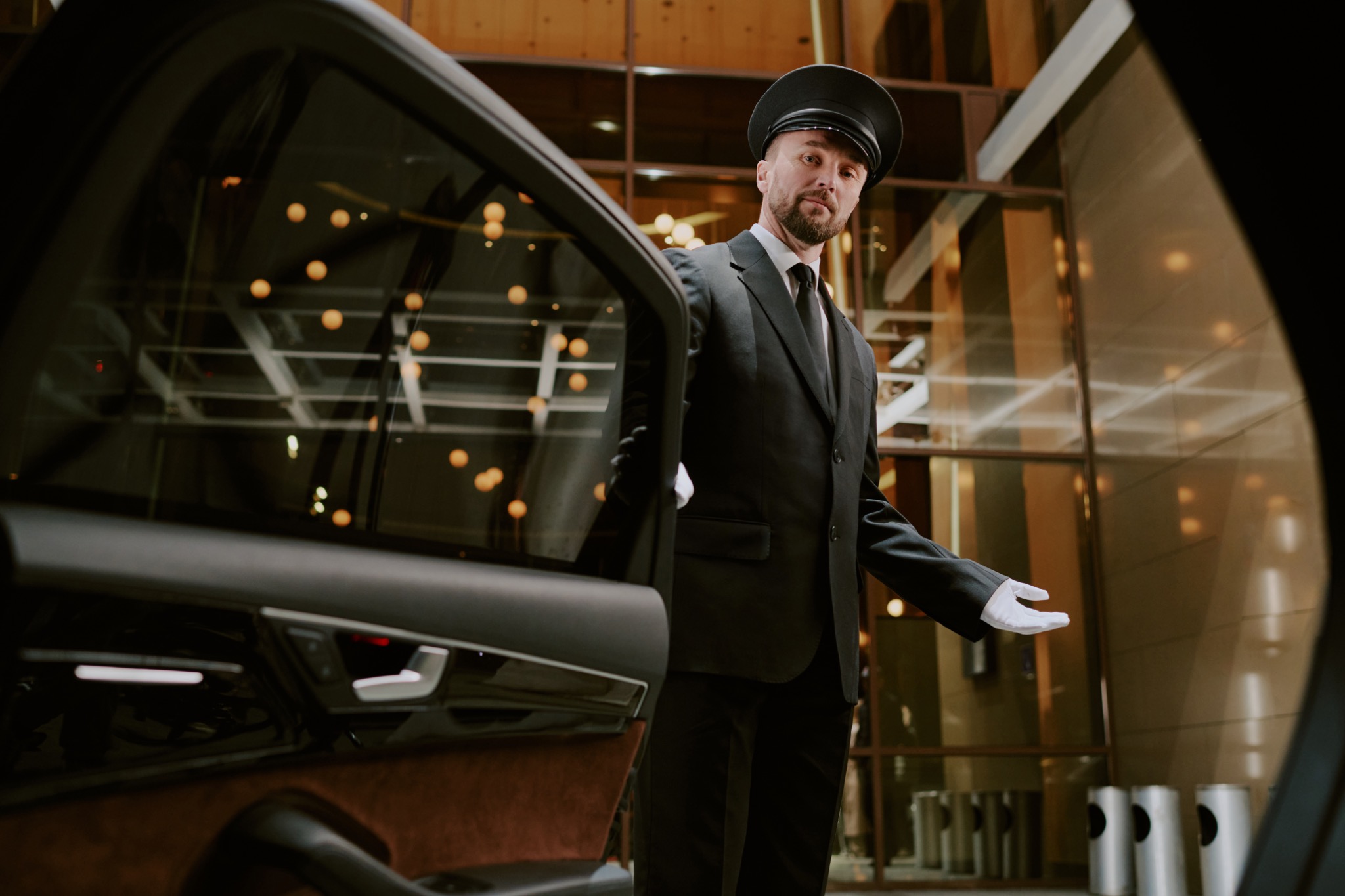 Chauffeur opening a car door representing private driver services.