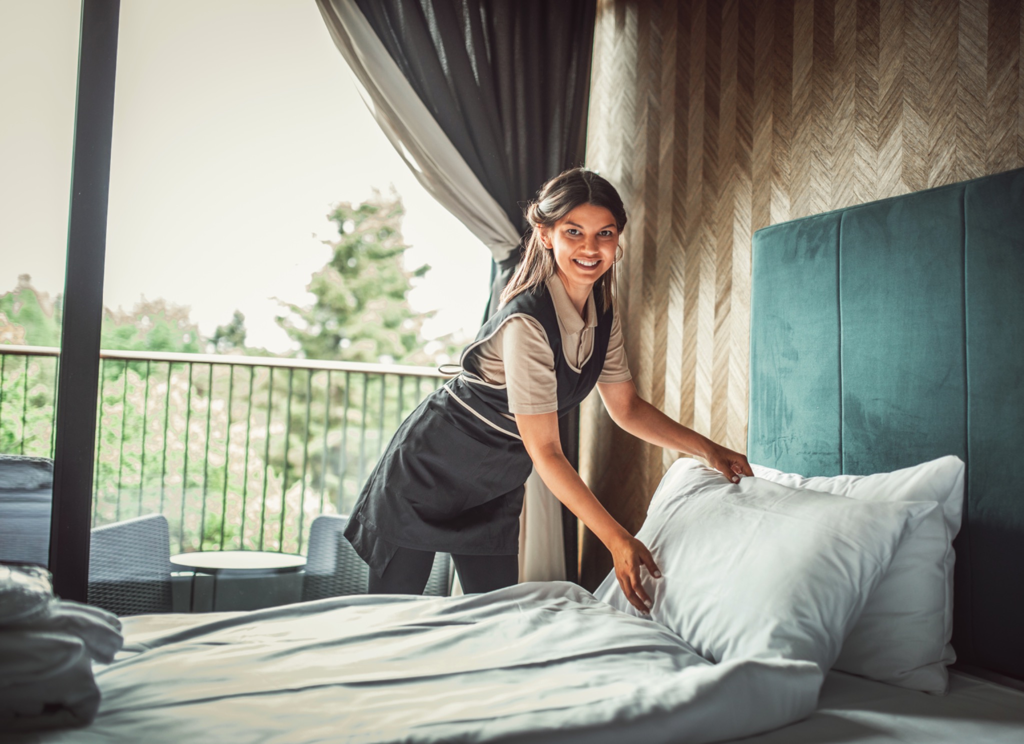 Housekeeping service preparing a bed representing domestic staffing.